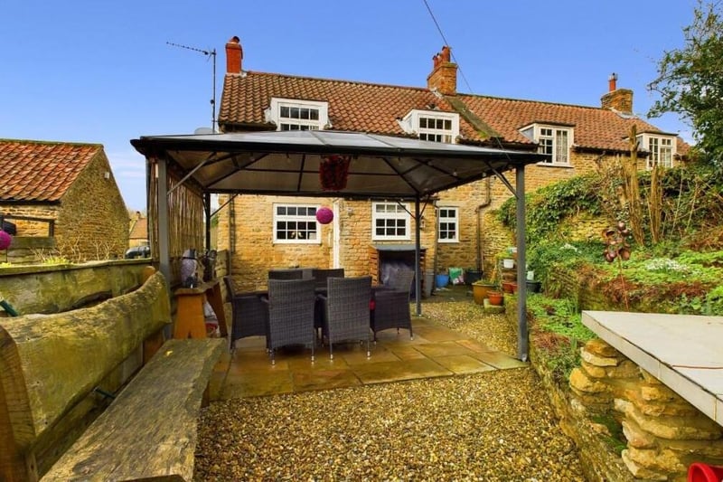 A covered seating area and rear view of the cottage in Ruston.