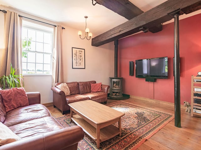 This comfortable sitting room has rustic tones, with wooden ceiling beams.