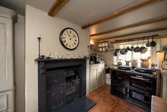 The beamed kitchen of the cottage has a working aga and an original feature range.