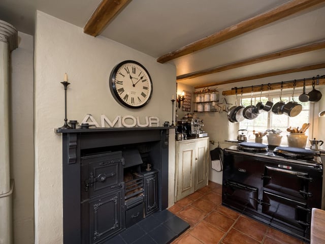 The beamed kitchen of the cottage has a working aga and an original feature range.