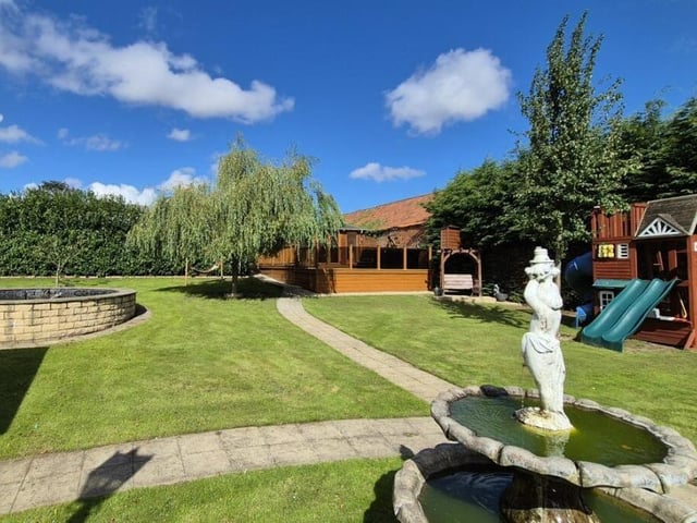 An extensive lawned garden with log cabin to the rear.