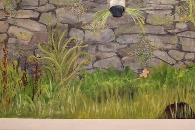 Donkey eating grass looking over a dry stone farmyard wall