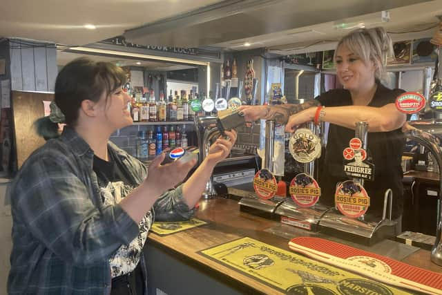 Claudia Bowes, Scarborough News reporter, being handed the old purse from Tara Giles, owner of the Belle Vue pub, on behalf of her mother.