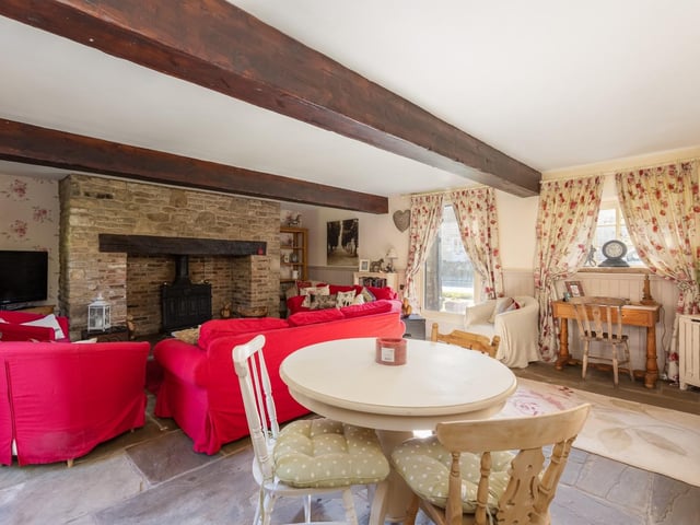 A beamed sitting and dining room with plenty of natural light.