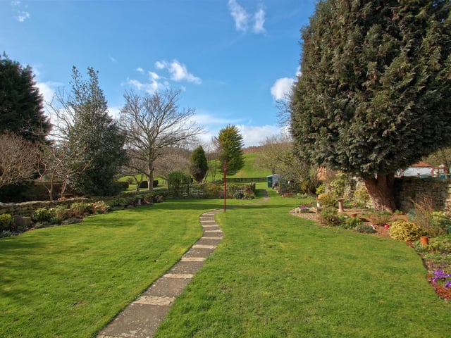Established flowers, plants and shrubs are planted in borders of the lawned garden.