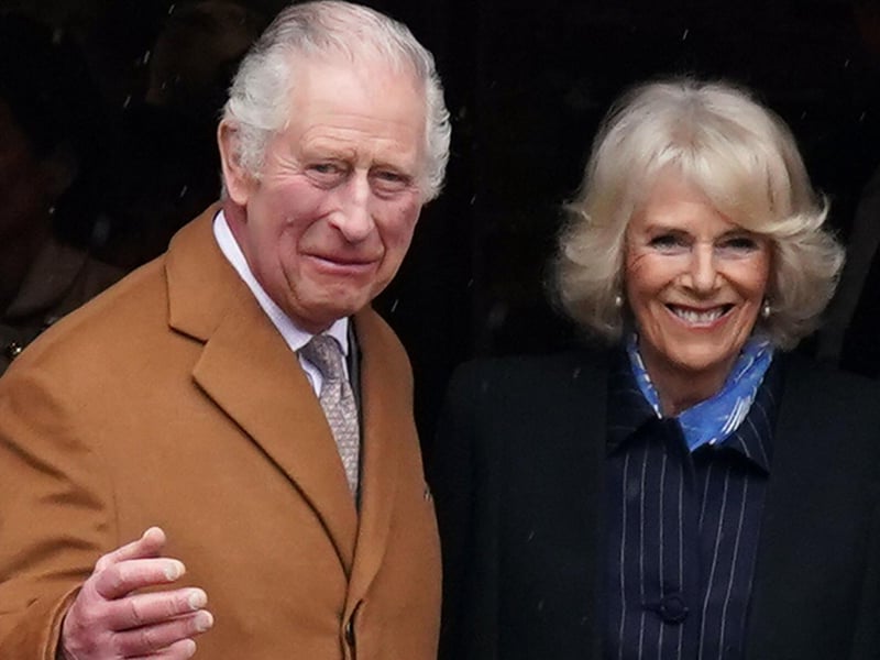 King Charles III and the Queen Consort smile and wave to the onlookers.