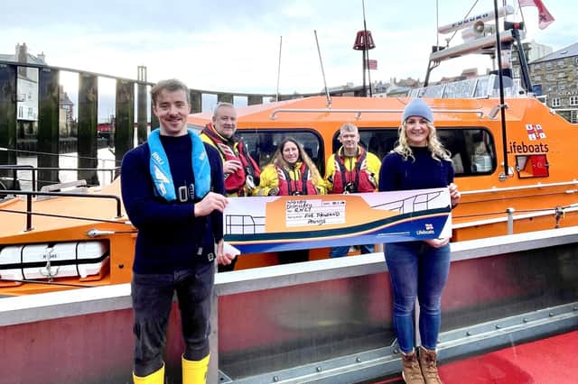 Volunteer Luke and his partner Jess present a cheque for £5000 to Whitby Lifeboat Station Image:RNLI