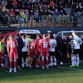 Darlington FC and Scarborough Athletic players leave the field along with the match officials.