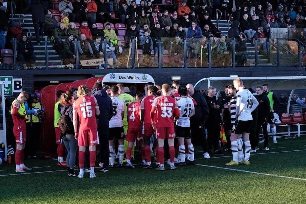 Darlington FC and Scarborough Athletic players leave the field along with the match officials.