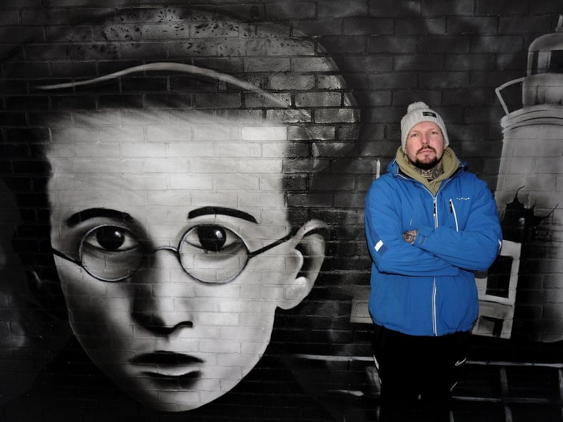 Artist Rew Nurse poses with the mural he painted.