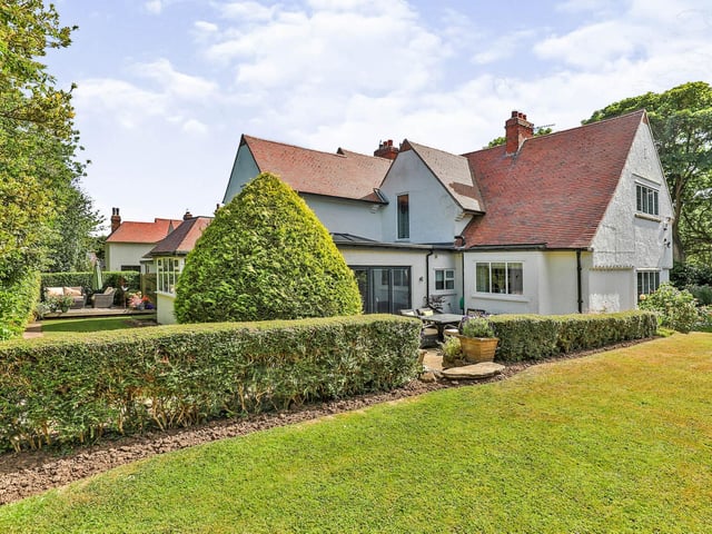 Well maintained lawned gardens with patio areas have established trees, shrubs and flowers.