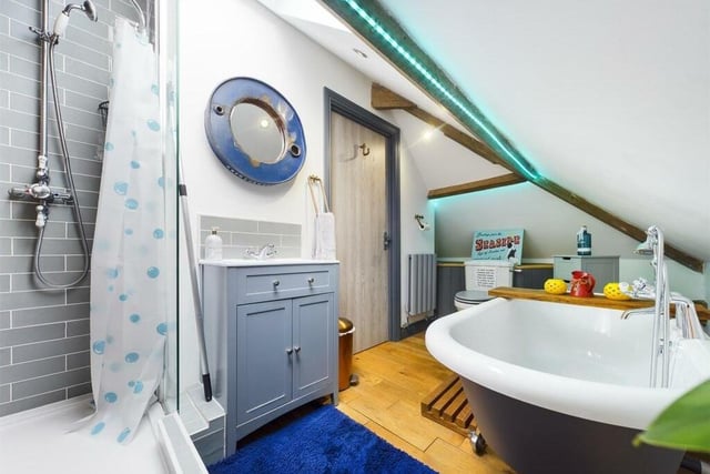 An appealing bathroom, with large roll-top bath tub, and a walk-in shower.