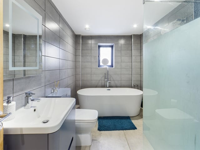 A freestanding bath is part of the suite within this house bathroom