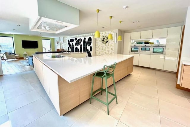 A spectacular open plan kitchen includes a large island unit, three integrated ovens, and a drinks area with ntegrated coffee machine and wine fridge.
