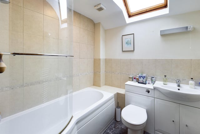 A wash basin within vanity unit, and bath with shower are included within this modern suite.