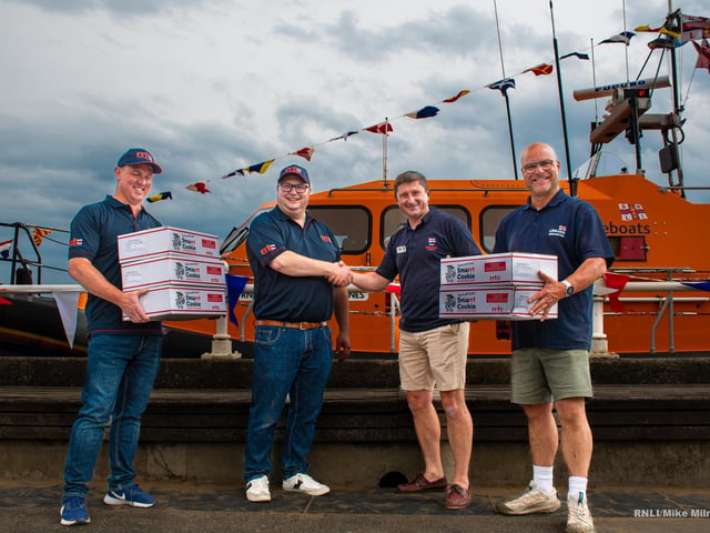RRT (Rapid Response Team UK) hand over energy bars to Andy Rodgers (Station Coxswain) and far right, Jake Bennett (Lifeboat Operations Manager).