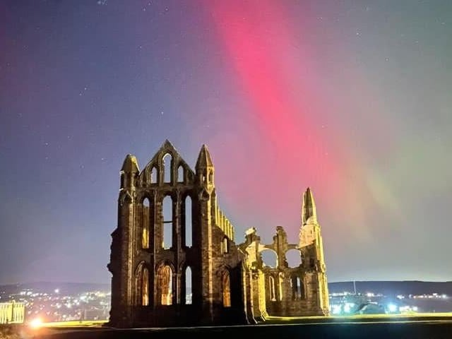 Whitby Abbey framed by the colourful sky.