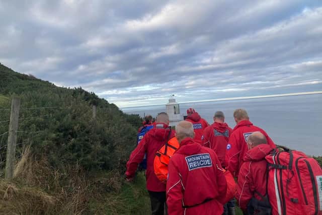 Mountain recue team members carry the casualty to a waiting vehicle