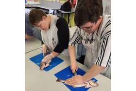 Bridlington School students Kole Kinder and Cody Ledger preparing a fish fillet, which will go towards their GCSE assessments.