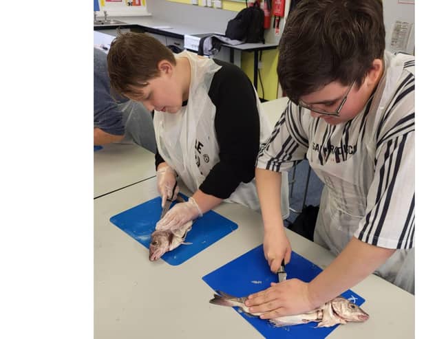 Bridlington School students Kole Kinder and Cody Ledger preparing a fish fillet, which will go towards their GCSE assessments.