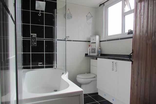 A stylish bathroom with kidney-shape bath and overhead shower.