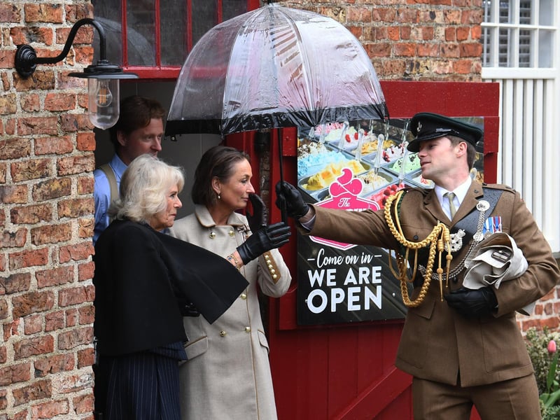 Passing Queen Consort Camilla an umbrella.