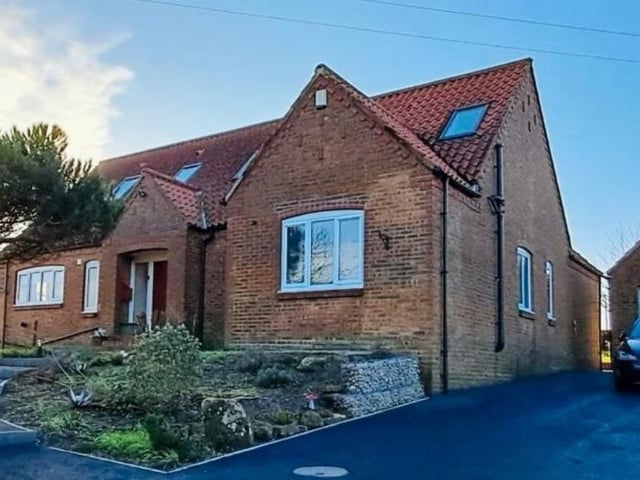 The front aspect of the property, that has a wide tarmac drive, and detached garage.
