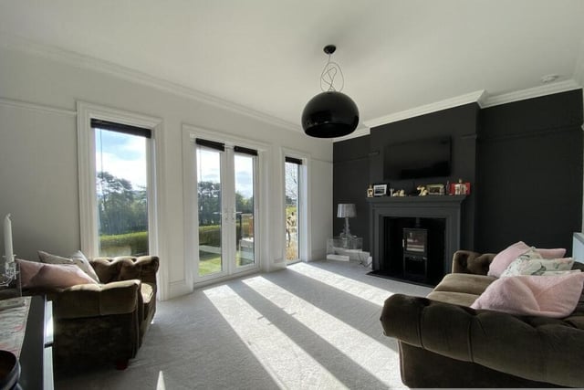 A reception room with wood burner stove and doors to outside.