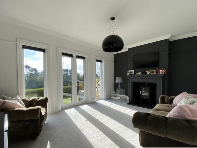 A reception room with wood burner stove and doors to outside.