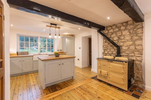 The beamed kitchen with exposed stone wall and central work island.