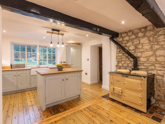 The beamed kitchen with exposed stone wall and central work island.