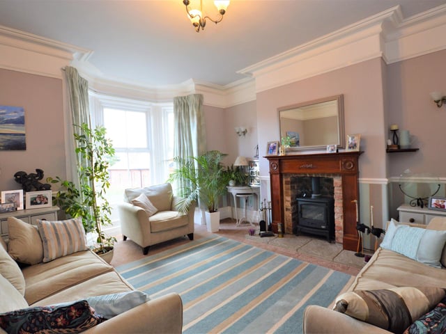 A bright and elegant reception room with central stove and feature fireplace.