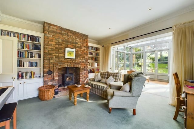 A rustic brick fireplace with stove is a feature in this reception room, with folding doors giving entry to the conservatory.