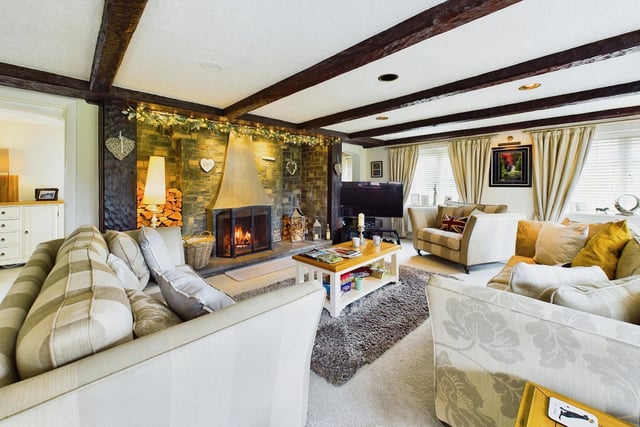 The beamed living room with an open fireplace has windows overlooking the garden.