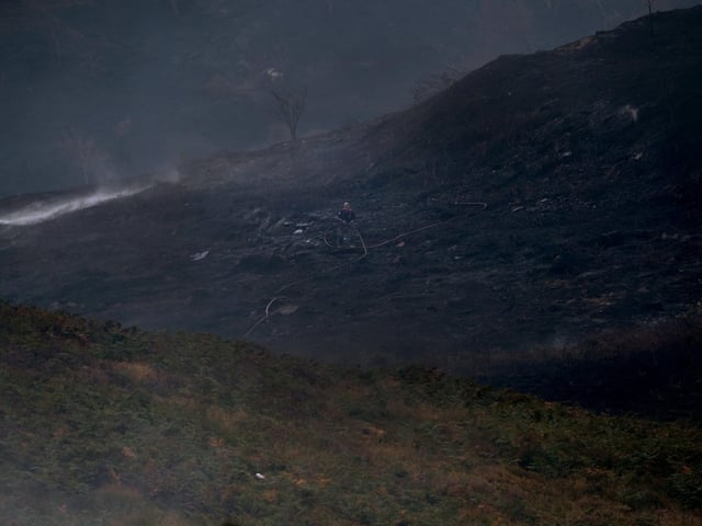 Firefighters work on the smouldering land