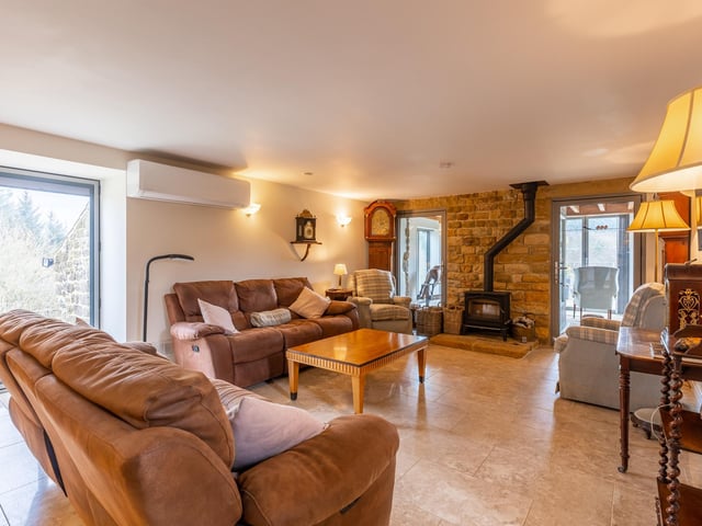 A spacious sitting room with cosy stove and doors leading outside.