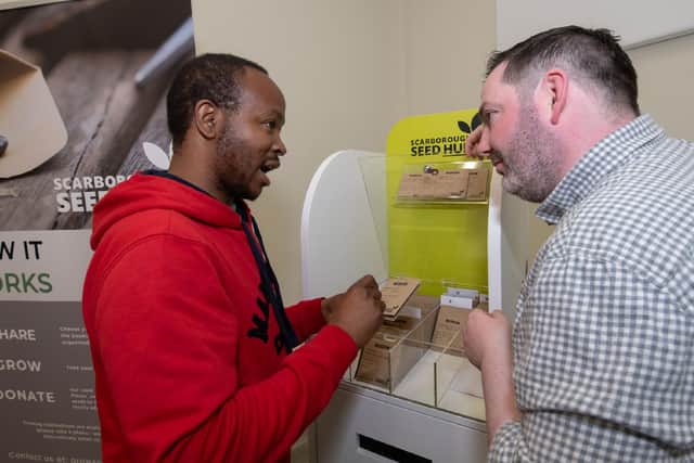 Darren Mancrief, founder and co-chairman of GROW Scarborough, explaining how the seed hub works with library visitor Athenkosi Nyengane.