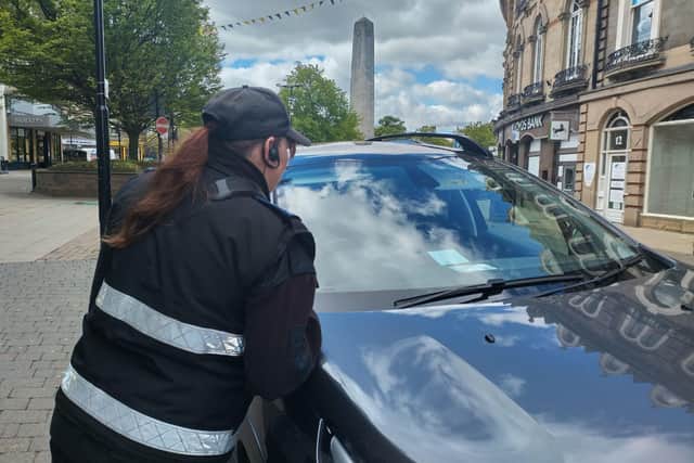 An officer inspects a car displaying a Blue Badge.