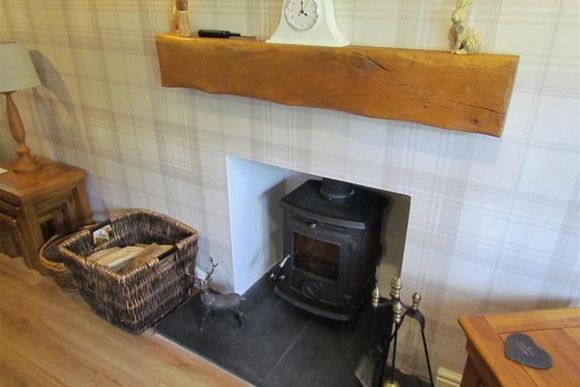 A feature fireplace with multi-fuel burner and tiled hearth is a focal point in the sitting room.