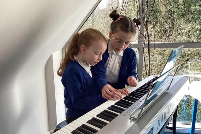 A pupil teaching another pupil some tips for the piano.