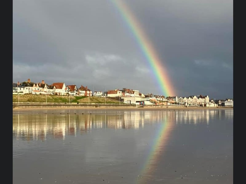 A colourful rainbow and it's reflection.