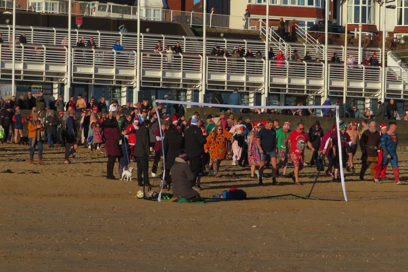 Here the participants in the dip are making their way onto a beach in Bridlington, getting ready to dash into the cold waters.