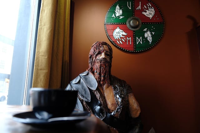Erik the Red, a Norse explorer who discovered Greenland, stands waiting for a coffee in the window and he was made by a local sculptor. The shield behind him was made by a regular at the cafe.