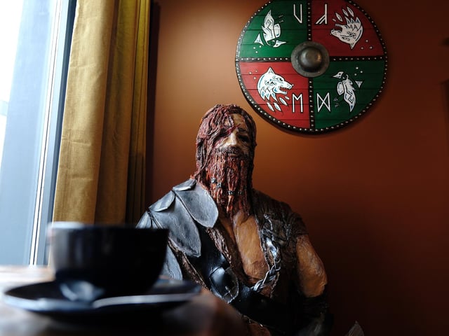 Erik the Red, a Norse explorer who discovered Greenland, stands waiting for a coffee in the window and he was made by a local sculptor. The shield behind him was made by a regular at the cafe.