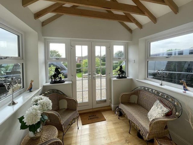 A roomy porch with exposed beams and double doors to outside.
