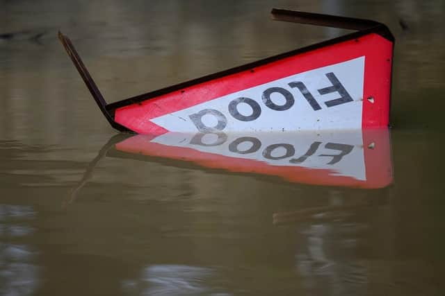 A flood warning sign lies in the water following heavy rain. (Pic credit: Leon Neal / Getty Images)