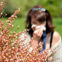 A woman blows her nose as the return of pleasant weather marks the arrival of allergenic pollen