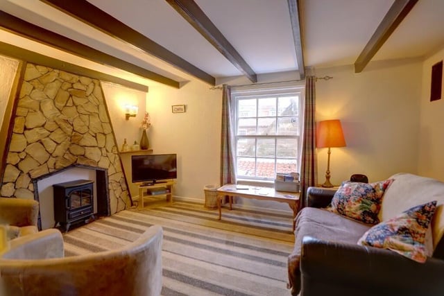 The beamed lounge with stone fireplace is on the fiirst floor of the cottage, with a seaward-facing window.