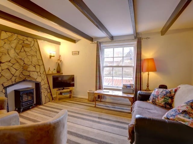 The beamed lounge with stone fireplace is on the fiirst floor of the cottage, with a seaward-facing window.
