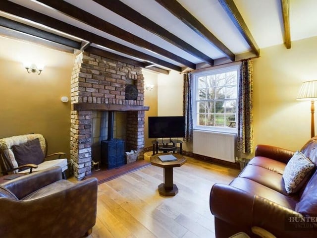 Space to relax in front of a rustic brick fireplace containing a warming stove.